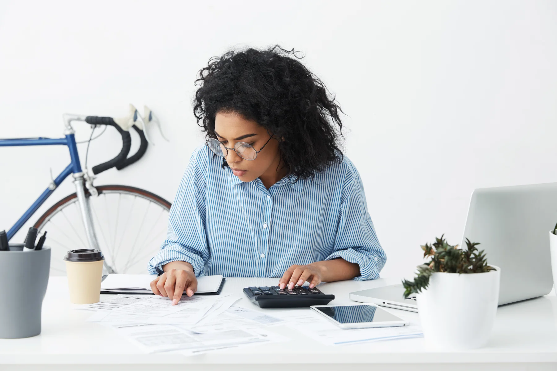 Woman calculating finances at a desk with papers.